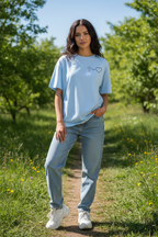 Frau trägt hellblaues Jesus Love Oversized T-Shirt mit Kreuz-Herz-Symbol